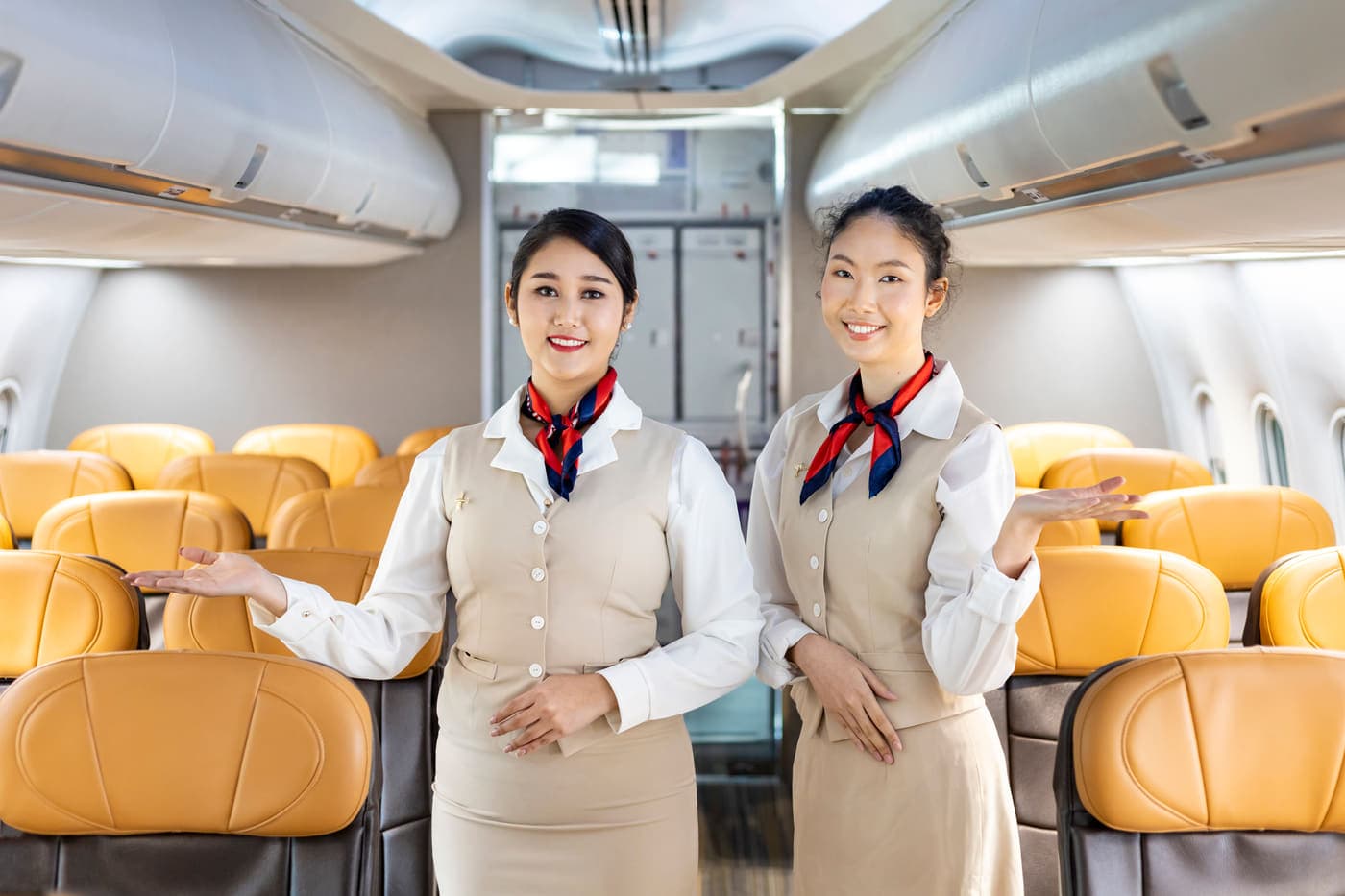 Two cabin crew welcoming passengers aboard from the aisle