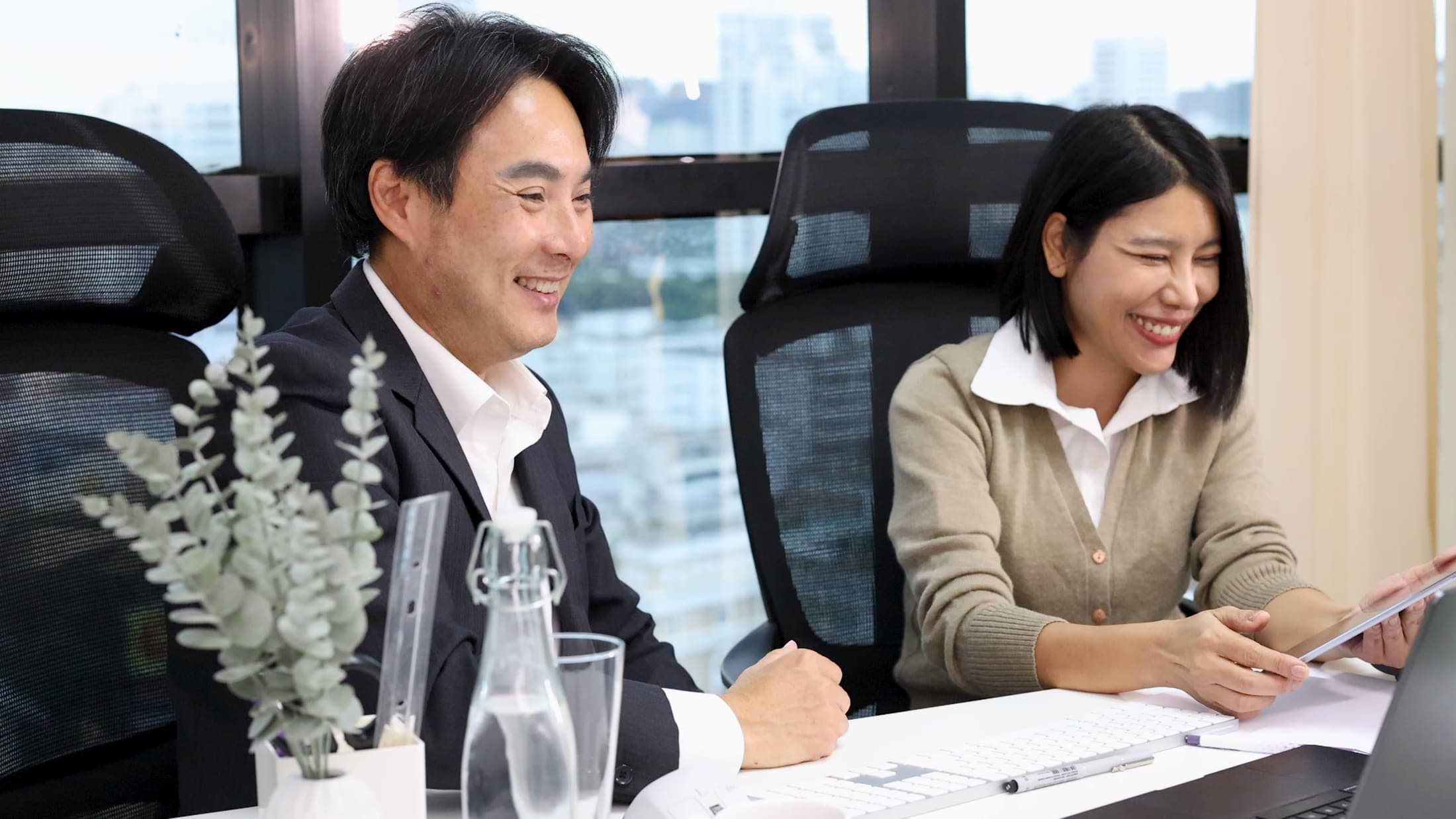 Two colleagues talking through a document in a bright meeting room