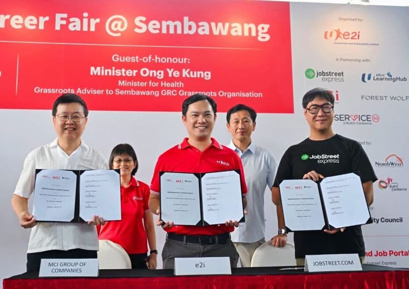 The three signatories holding up the signed memorandum of understanding on stage