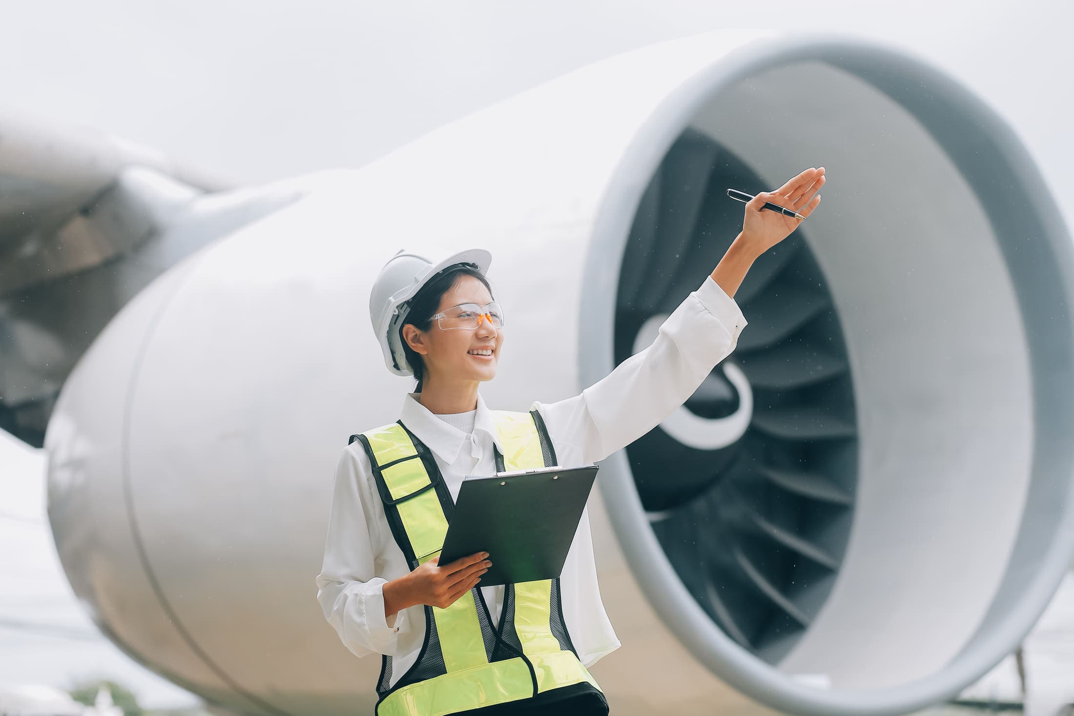 An aircraft engineer in a hi-vis vest inspecting a jet engine