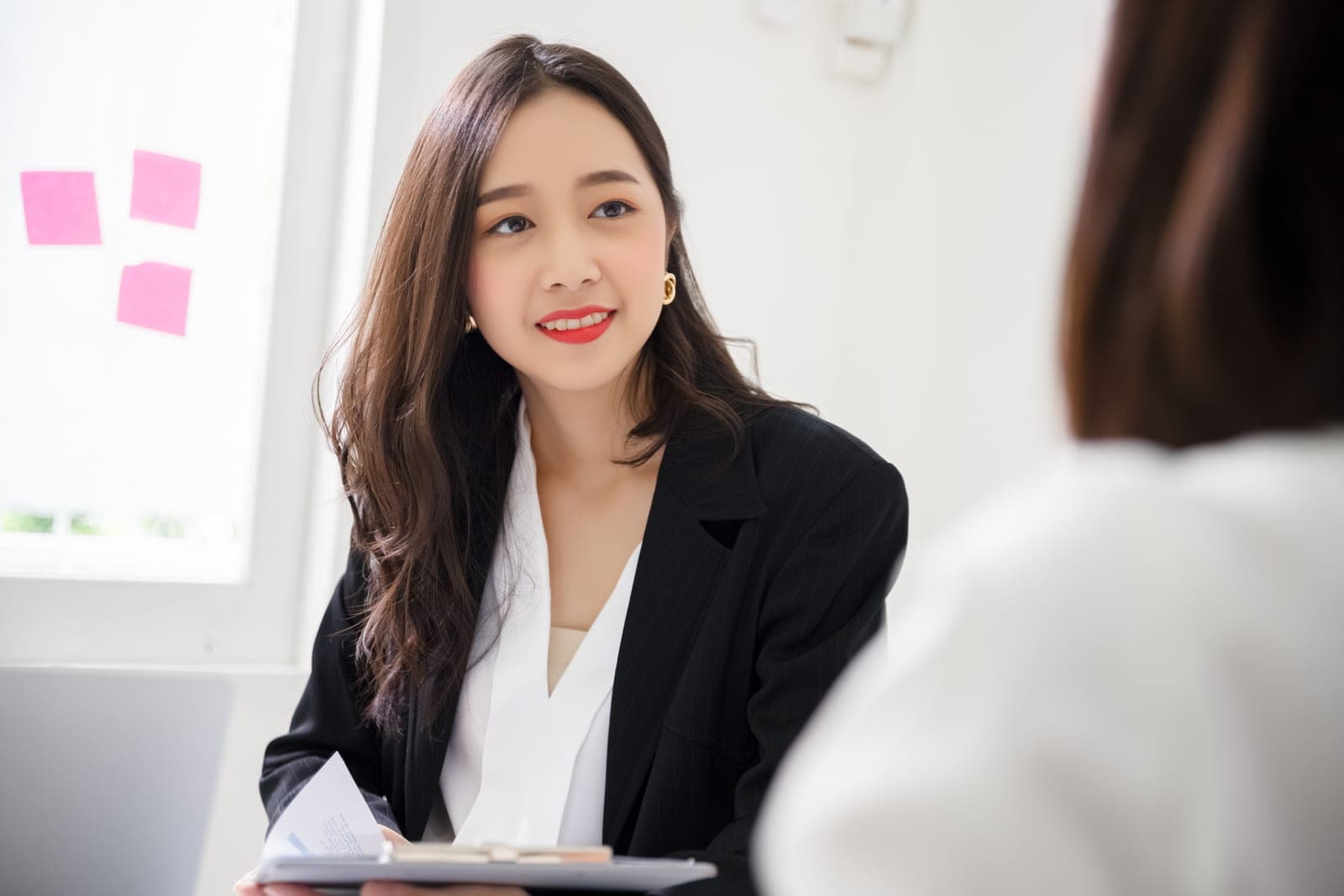A recruitment consultant holding a candidate's CV on a clipboard during an interview