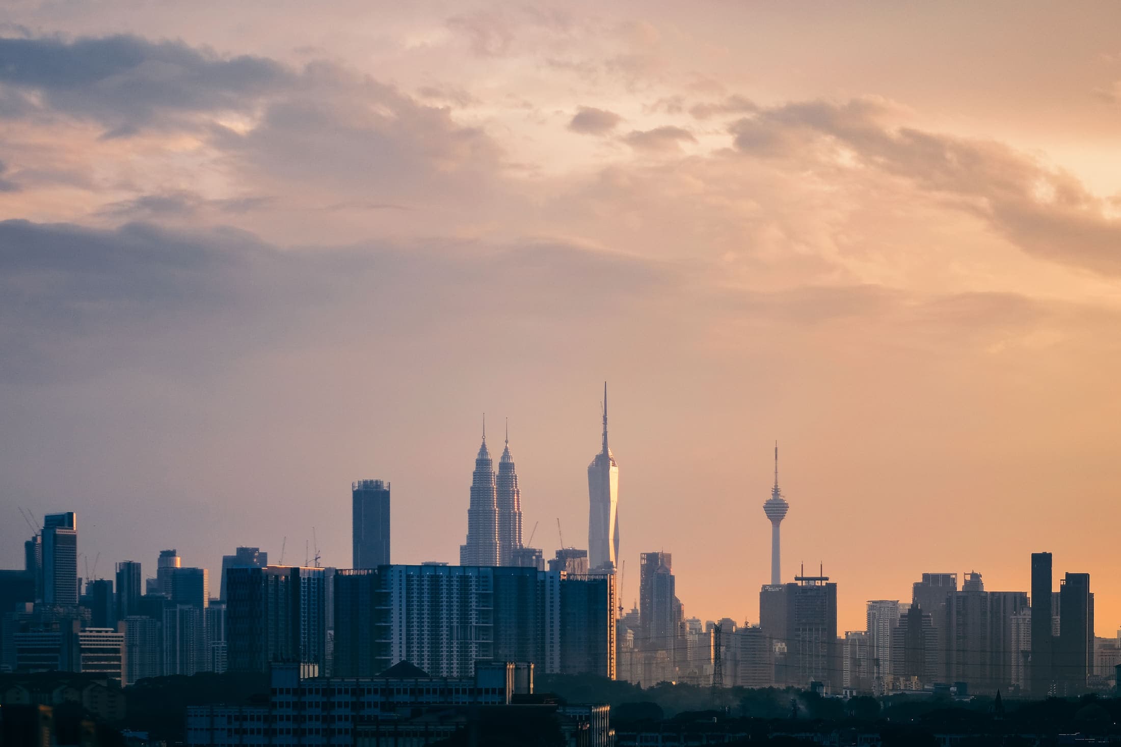 Kuala Lumpur at golden hour, the towers in silhouette against an orange sky
