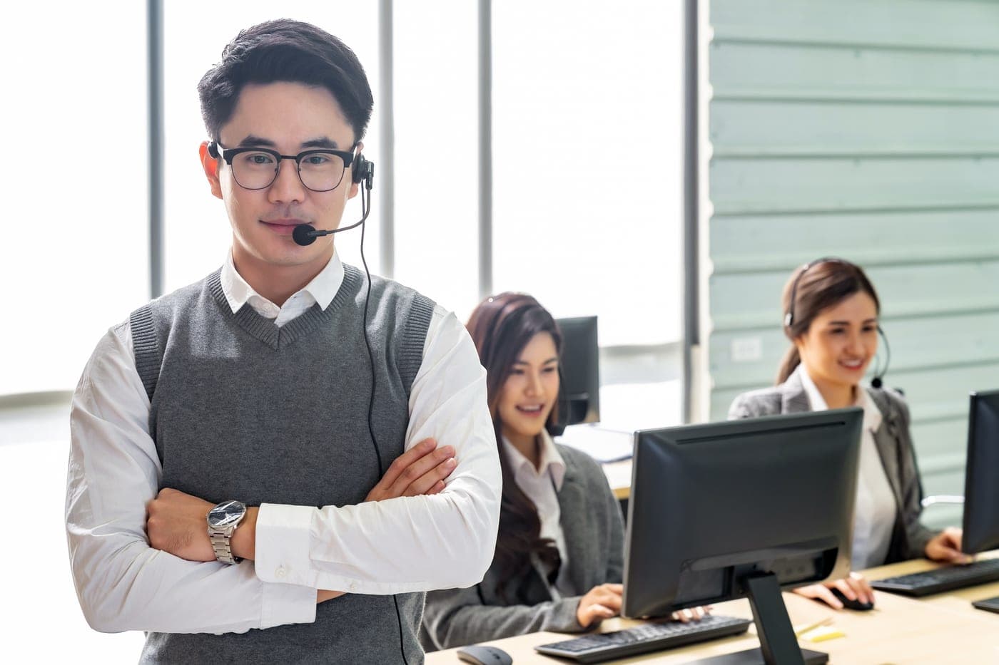 A customer-service agent wearing a headset, with two colleagues on calls in the background